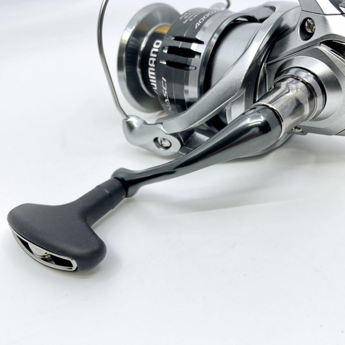 Silver fishing reel with black handle.