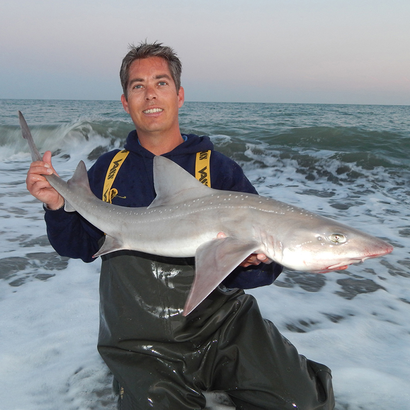 Man holding a large fish on the beach