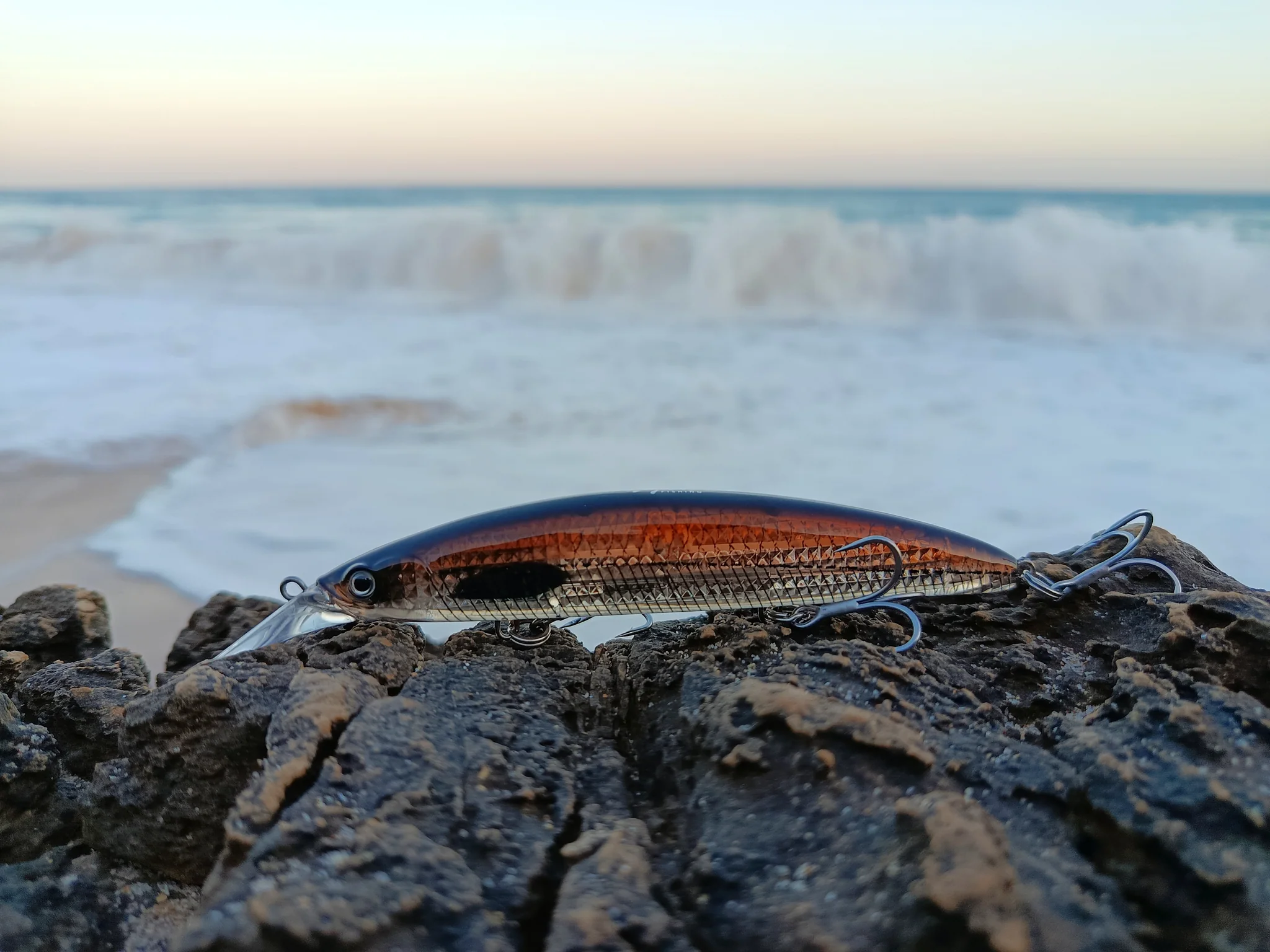 Fishing lure on rocks by seaside waves