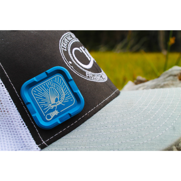 Close-up of cap with blue badge outdoors.