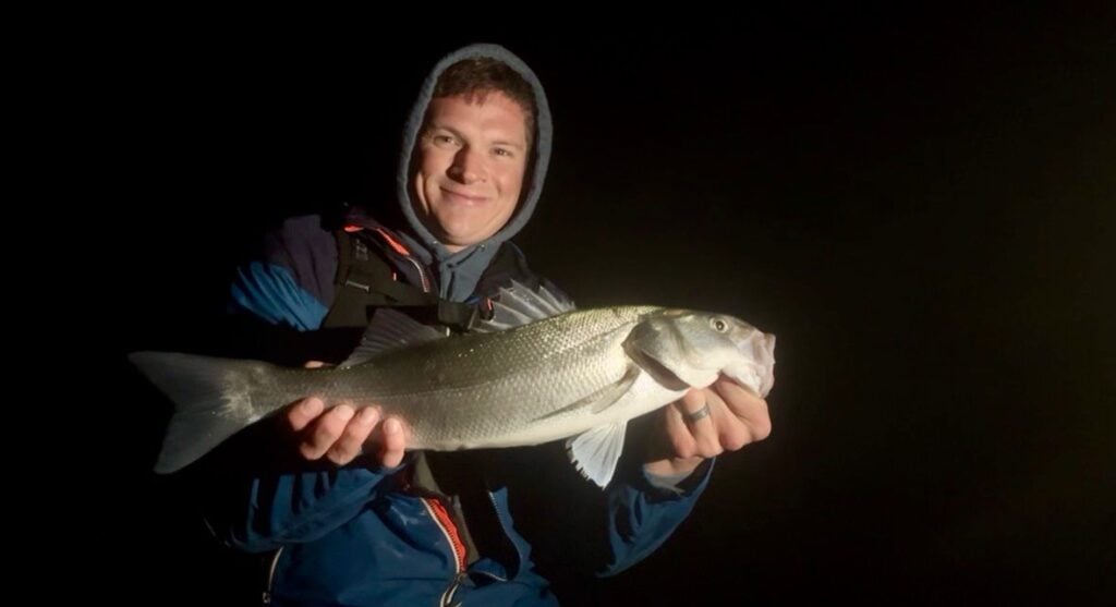 Person holding a large fish at night.